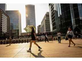 Un piéton utilise un parapluie pour se protéger du soleil, à Canary Wharf, lors d'une vague de chaleur à Londres, au Royaume-Uni, le lundi 18 juillet 2022. La chaleur extrême pourrait entraîner des pannes de courant, des vols annulés et peut être un danger pour la vie tout en le soi-disant avertissement Red Extreme est en place dans certaines parties du sud de l'Angleterre lundi et mardi.  Photographe : José Sarmento Matos/Bloomberg