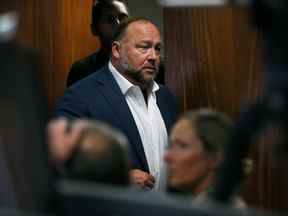 Alex Jones entre dans la salle d'audience devant Scarlett Lewis et Neil Heslin, les parents de Jesse Lewis, victime de la fusillade de Sand Hook, âgé de 6 ans, au palais de justice du comté de Travis à Austin, Texas, le 28 juillet 2022.