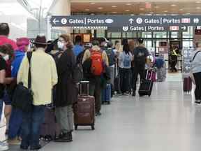 Les gens font la queue avant d'entrer dans la sécurité à l'aéroport international Pearson de Toronto le vendredi 5 août 2022. Le comité des transports de la Chambre des communes tient une réunion d'urgence aujourd'hui pour discuter de l'opportunité de poursuivre une enquête sur les retards de l'aéroport et les annulations de vols. LA PRESSE CANADIENNE/Nathan Denette