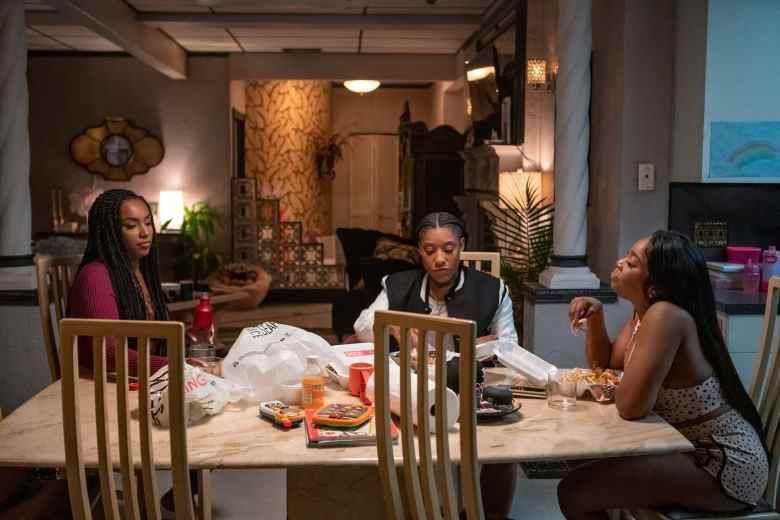 Trois femmes sont assises autour d'une table à manger et mangent des plats à emporter ;  encore de 