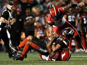 Le quart-arrière du Rouge et Noir d'Ottawa Caleb Evans est limogé par le joueur de ligne défensive des Stampeders de Calgary Shawn Lemon à la Place TD à Ottawa le vendredi 5 août 2022.