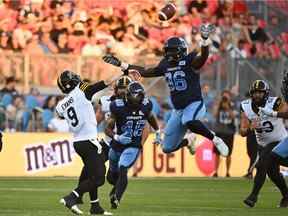 Le quart-arrière des Tiger-Cats de Hamilton Dane Evans obtient un laissez-passer contre le joueur de ligne des Argonauts de Toronto Dan Acheampong lors de la première mi-temps à Toronto le samedi 6 août 2022. Les Argos ont gagné 34-20.