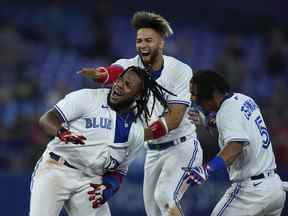 Le joueur de premier but des Blue Jays de Toronto Vladimir Guerrero Jr. (27) réagit avec ses coéquipiers Lourdes Gurriel Jr. (13) et Santiago Espinal (5) après avoir frappé le match gagnant du RBI pour vaincre les Orioles de Baltimore lors de la dixième manche de la Ligue américaine, action de baseball MLB en Toronto le mercredi 15 juin 2022.