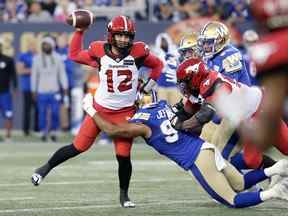 Le quart-arrière des Stampeders de Calgary Jake Maier se débarrasse du ballon alors qu'il est frappé par l'ailier défensif des Blue Bombers de Winnipeg Jackson Jeffcoat au IG Field de Winnipeg le jeudi 25 août 2022.