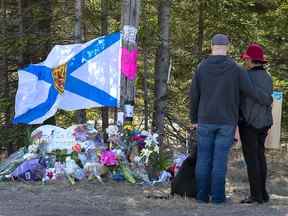 Un couple visite un mémorial de fortune aux victimes des fusillades de masse en Nouvelle-Écosse à Portapique, en Nouvelle-Écosse, le 22 avril 2020. Une culture d'ouverture parmi la police plutôt que l'opacité aurait bien pu sauver des vies.