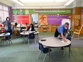 Un homme désinfecte les surfaces de table dans une classe de maternelle à l'école publique Hunter's Glen Junior pendant la pandémie de COVID-19 à Scarborough, en Ontario, le lundi 14 septembre 2020.