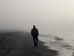 Homme seul marchant sur une plage brumeuse