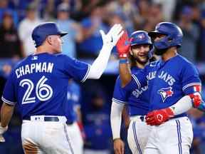 Matt Chapman des Blue Jays, à gauche, et Bo Bichette, au centre, célèbrent un circuit de trois points de Teoscar Hernandez, à droite, en sixième manche contre les Cubs au Rogers Centre de Toronto, le mardi 30 août 2022.