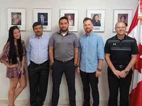 L'équipage de conduite de Pivot Airlines prend une photo devant des portraits de dirigeants canadiens sur le mur de l'ambassade du Canada en République dominicaine.