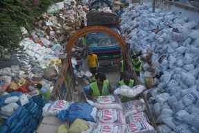 Des bénévoles de la Charity Al-Khidmat Foundation chargent des sacs de secours sur des camions pour les personnes touchées par les inondations à Karachi le 3 septembre 2022.