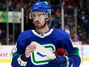 Conor Garland regarde depuis le banc lors de leur match de la LNH contre les Blackhawks de Chicago au Rogers Arena le 21 novembre 2021 à Vancouver.