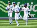 Les Blue Jays de Toronto, de gauche à droite, Lourdes Gurriel Jr., Bradley Zimmer et Teoscar Hernandez arrivent du champ extérieur après avoir vaincu les Tigers de Detroit lors d'une action de baseball de la Ligue américaine à Toronto, le dimanche 31 juillet 2022.  