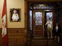 Un portrait de la reine Elizabeth II est drapé d'un ruban noir alors que les gens visitent l'Assemblée législative de Queen's Park de l'Ontario, le 9 septembre 2022 à Toronto.