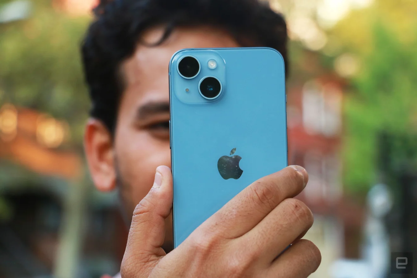 L'iPhone 14 s'est tenu en l'air avec un homme derrière lui, montrant les deux caméras arrière.