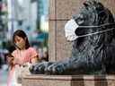 Une statue de lion porte un masque sur une photo d'archive de Tokyo prise le 5 août 2021. Trois spécialistes des maladies infectieuses écrivent qu'un débat scientifique valable sur le COVID-19 a été bâillonné par ceux qui le jugent 