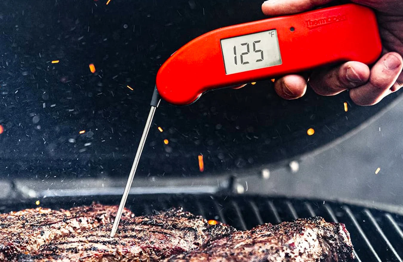 Le thermomètre ThermoWorks Thermapen One prenant la température d'une pièce de viande sur un gril.