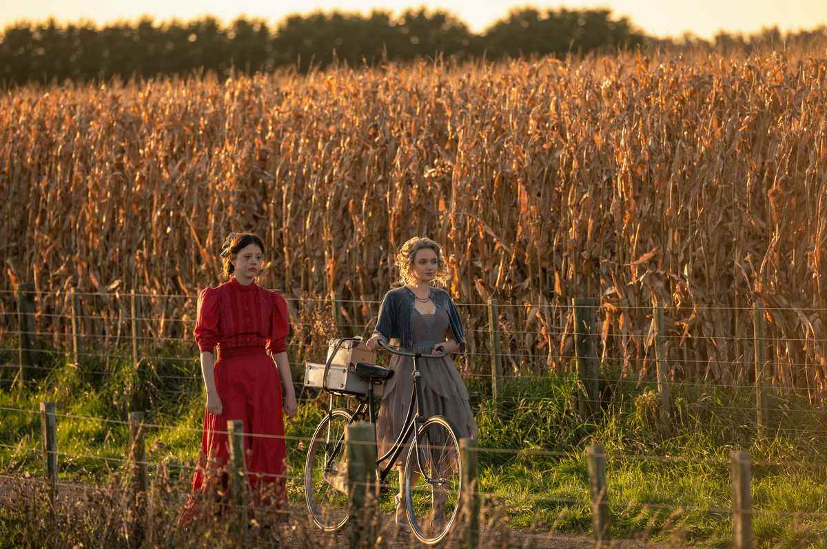 Pearl (Mia Goth) dans Ti West's Pearl marche aux côtés de sa belle-sœur Misty (Emma Jenkins-Purro) au bord d'un vaste champ de maïs mort à Pearl