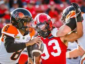 Le quart-arrière des Lions de la Colombie-Britannique Vernon Adams lance sous la pression du joueur de ligne défensive des Stampeders de Calgary Romeo McKnight au stade McMahon de Calgary le samedi 17 septembre 2022.