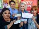 Les candidates au conseil du COPE (de gauche à droite) Nancy Trigueros, Breen Ouellette, Jean Swanson et Tanya Webking tiennent des chèques que le parti a reçus dans une enveloppe portant le logo de Concord Pacific, à leur bureau de campagne à Vancouver.