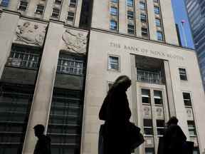 Des piétons passent devant l'édifice de la Banque de Nouvelle-Écosse dans le quartier financier de Toronto.