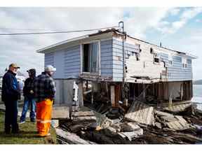 Des gens examinent les restes d'une maison après l'arrivée de l'ouragan Fiona à Port Aux Basques, Terre-Neuve, le 25 septembre 2022.