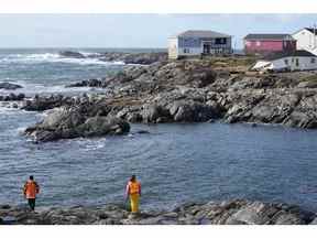 Une équipe de recherche et de sauvetage examine le littoral alors qu'elle recherche un individu emporté en mer après l'arrivée de l'ouragan Fiona à Port Aux Basques, Terre-Neuve, le 25 septembre 2022.