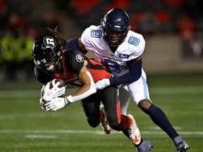 Le receveur des Redblacks Ryan Davis se fait plaquer par le demi défensif des Argonauts DaShaun Amos dans la première moitié du match de samedi.