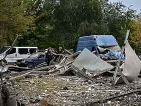 Des policiers ukrainiens contrôlent des voitures endommagées par une frappe de missile sur une route près de Zaporizhzhia le vendredi 30 septembre 2022, au milieu de l'invasion russe de l'Ukraine.