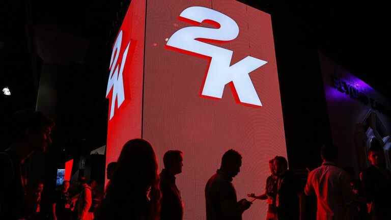 Attendees walk past signage for 2K Games Inc. during the E3 Electronic Entertainment Expo in Los Angeles, California, U.S., on Tuesday, June 10, 2014. E3, a trade show for computer and video games, draws professionals to experience the future of interactive entertainment as well as to see new technologies and never-before-seen products.