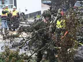 Cpl.  Owen Donovan des Cape Breton Highlanders enlève les broussailles sous la direction des responsables de Nova Scotia Power le long du chemin Steeles Hill à Glace Bay, en Nouvelle-Écosse, le lundi 26 septembre 2022.