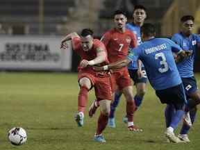 Liam Millar du Canada, à gauche, et Roberto Dominguez du Salvador, s'affrontent pour le ballon lors d'un match de soccer de qualification pour la Coupe du Monde de la FIFA, Qatar 2022 au stade Cuscatlan à San Salvador, El Salvador, le mercredi 2 février 2022.