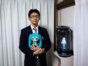 Sur cette photo prise le 10 novembre 2018, le japonais Akihiko Kondo pose à côté d'un hologramme de la chanteuse japonaise de réalité virtuelle Hatsune Miku