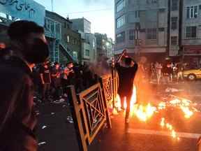 Les gens allument un feu lors d'une manifestation contre la mort de Mahsa Amini, une femme décédée après avoir été arrêtée par la République islamique "police des mœurs," à Téhéran, Iran, le 21 septembre 2022.