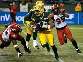 Le quart-arrière des Elks d'Edmonton, Kai Locksley (10), court contre Folarin Orimolade (9) et Thomas Costigan (95) des Stampeders de Calgary lors de la deuxième mi-temps de l'action de la LCF au Commonwealth Stadium d'Edmonton, le jeudi 7 juillet 2022.