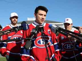 Nick Suzuki s'adresse aux journalistes après avoir été nommé nouveau capitaine des Canadiens de Montréal lors du tournoi de golf annuel de l'équipe à Laval, au nord de Montréal, le lundi 12 septembre 2022. Il était accompagné des capitaines adjoints Joel Edmundson, à gauche et Brendan Gallagher.