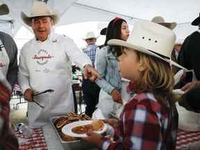 Le premier ministre de l'Alberta, Jason Kenney, à gauche, prépare des crêpes lors de son dernier petit-déjeuner annuel du premier ministre du Stampede en tant que premier ministre à Calgary, en Alberta, le lundi 11 juillet 2022.