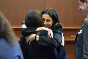 L'avocate Joelle Rich embrasse l'avocate Camille Vasquez, dos à la caméra, sous le regard de l'avocat Ben Chew, à droite, à la fin de la procédure quotidienne au palais de justice du circuit du comté de Fairfax à Fairfax, en Virginie, le lundi 16 mai 2022.