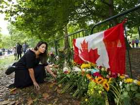 Le Canadien Kersten Samolczyk, qui réside maintenant au Royaume-Uni, place des fleurs près d'un drapeau canadien alors que des milliers de personnes en deuil déposent des fleurs alors que les gens rendent hommage près des portes du palais de Buckingham à Londres le dimanche 11 septembre 2022. La reine Elizabeth II, la plus longue de Grande-Bretagne- monarque régnant et un rocher de stabilité pendant une grande partie d'un siècle turbulent, est décédé le jeudi 8 septembre 2022, après 70 ans sur le trône.  Elle avait 96 ans.