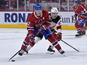 L'attaquant des Canadiens de Montréal Cole Caufield joue la rondelle tandis que l'attaquant des Devils du New Jersey Andreas Johnsson défend en première période au Centre Bell le lundi 26 septembre 2022.