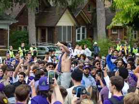 Des foules se rassemblent pour regarder un fêtard effectuer des sauts périlleux arrière sur un trampoline qui a été transporté sur une pelouse de l'avenue Broughdale lors des festivités des Retrouvailles près du campus de l'Université Western.  Photo prise le samedi 24 septembre 2022. (Calvi Leon/The London Free Press)