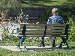 Une personne âgée est assise sur un banc au bord de la rivière Humber à Toronto.