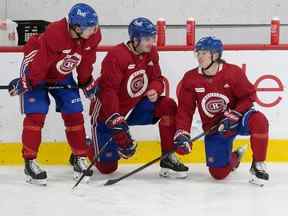 Kirby Dach des Canadiens de Montréal est entouré de Jake Evans, à gauche, et de Cole Caulfield lors de la première journée du camp d'entraînement à Brossard le 22 septembre 2022.