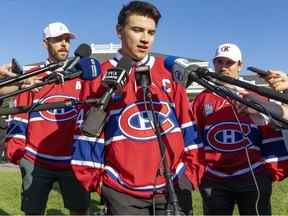 Les Canadiens de Montréal Nick Suzuki sont accompagnés des capitaines adjoints Joel Edmondson, à gauche, et Brendan Gallagher après avoir été nommé le dernier capitaine de l'équipe lors de leur tournoi de golf annuel à Laval, au nord de Montréal, le dimanche 11 septembre 2022.