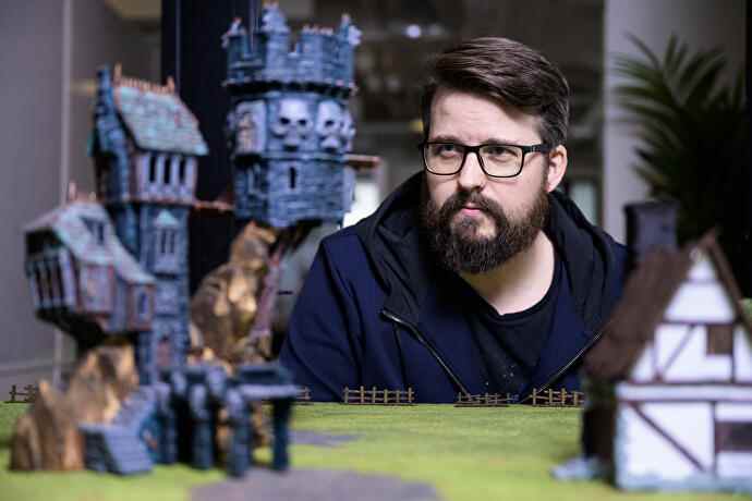 Aperçu de Darktide - Mats Andersson de Fatshark étudie une disposition de table de bâtiments et d'objets Warhammer