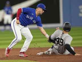 Le joueur de premier but des Yankees de New York Anthony Rizzo (48 ans) est surpris en train de voler par le joueur de deuxième but des Blue Jays de Toronto Whit Merrifield (à gauche) lors de la huitième manche au Rogers Centre.