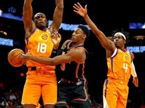 Le garde des New York Knicks RJ Barrett (9) passe le ballon contre le centre des Phoenix Suns Bismack Biyombo (18) et le garde Aaron Holiday (4) au cours de la seconde mi-temps au Footprint Center le 4 mars 2022.