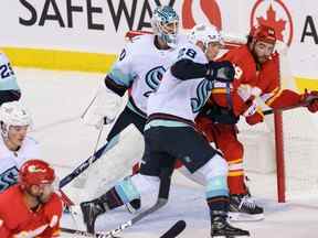 L'attaquant des Flames de Calgary Dillon Dube affronte le défenseur du Kraken de Seattle Carson Soucy devant le gardien de but Martin Jones au Scotiabank Saddledome de Calgary le lundi 3 octobre 2022.