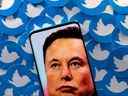 Une image d'Elon Musk est vue sur un smartphone placé sur des logos Twitter imprimés dans cette illustration.  