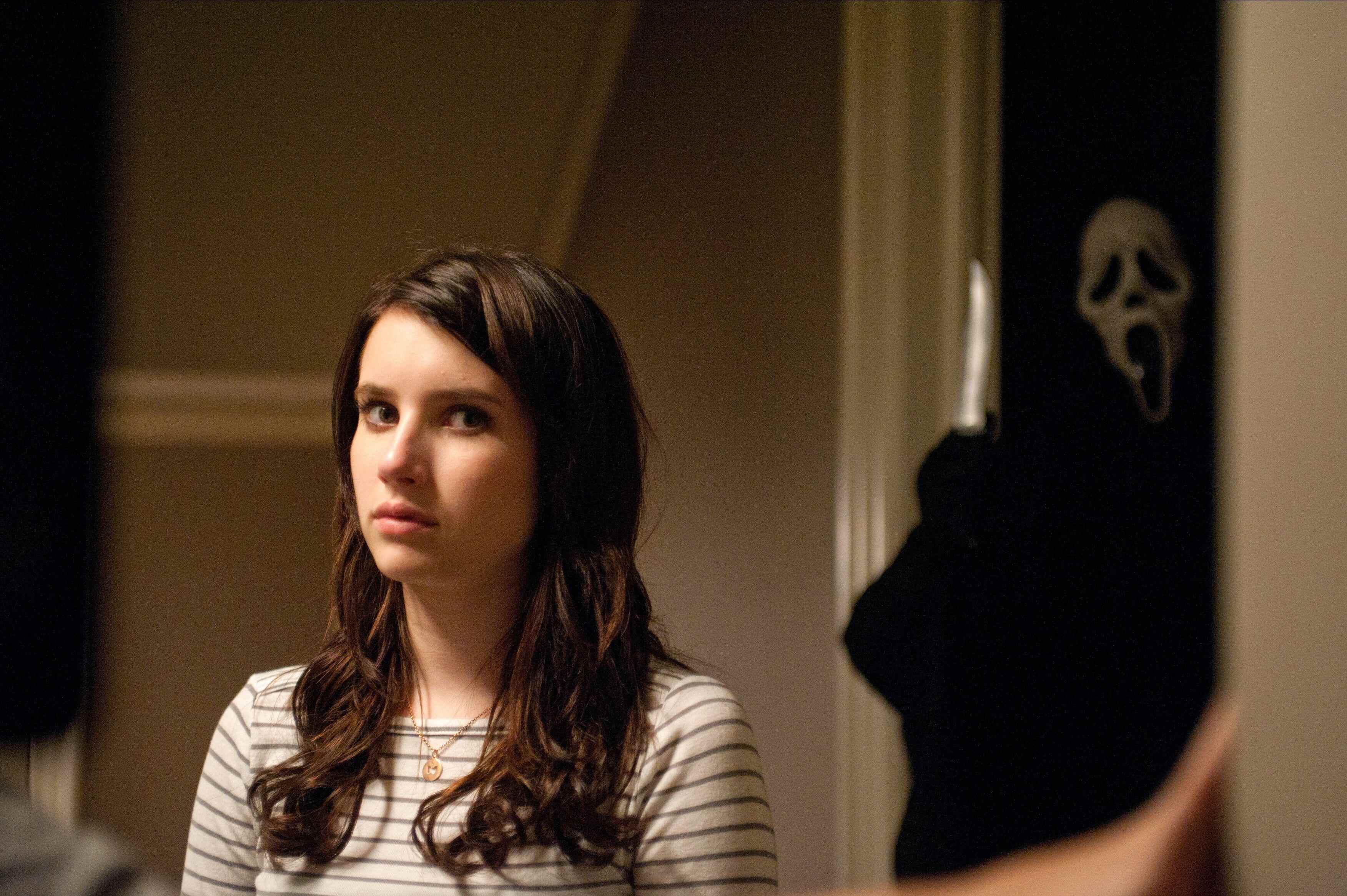 Emma Roberts dans le rôle de Jill Roberts, avec Ghostface derrière elle dans Scream 4