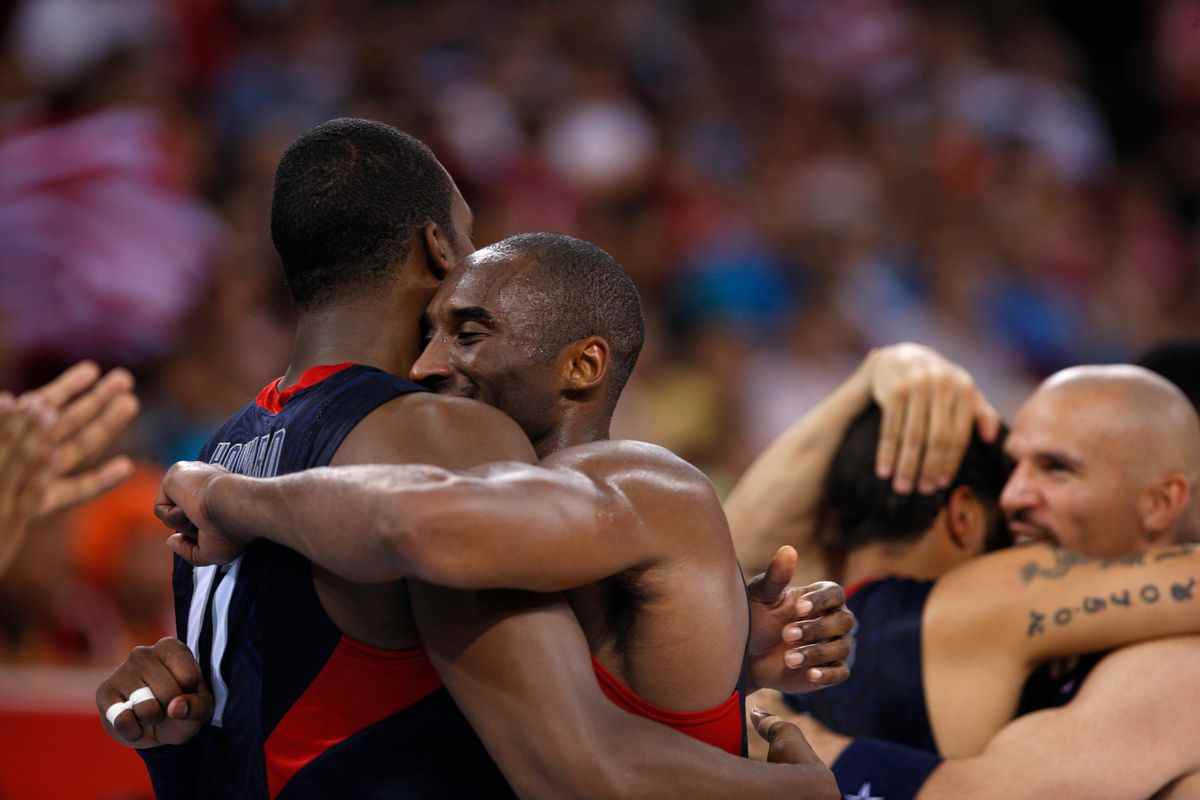 Une photo de Kobe Bryant étreignant son coéquipier Dwight Howard sur le terrain avec Jason Kidd en arrière-plan dans The Redeem Team.